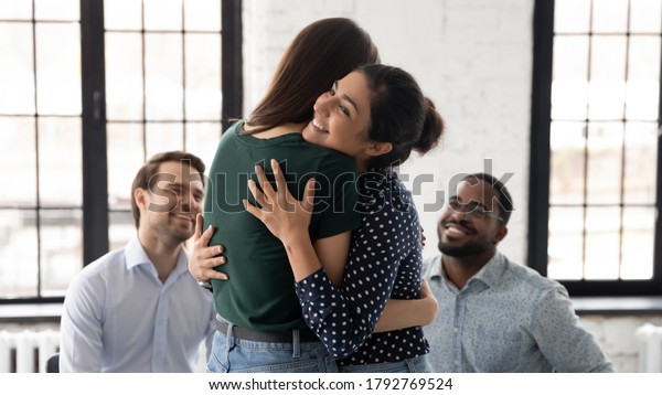Smiling Indian psychologist hugging patient at\
group counselling session, giving psychological help, expressing\
support and empathy, helping overcome problems, depressing or\
addictions treatment