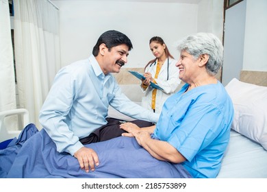 Smiling Indian Son Visit His Mother At Hospital, Old Female Patient Talking To Man At Clinic. Elderly People Health Care Concept.