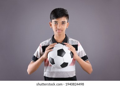 Smiling Indian teen boy holding soccer ball or football	
