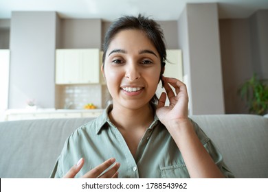 Smiling indian woman professional online teacher, telesales agent, remote tutor or call center operator wearing headset look at webcam conference video call center at home office. Headshot portrait.