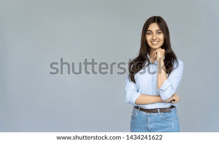 Smiling indian young business woman wear blue jeans shirt looking at camera isolated on grey blank studio background with copy space, happy pretty hindu female student posing on gray wall, portrait