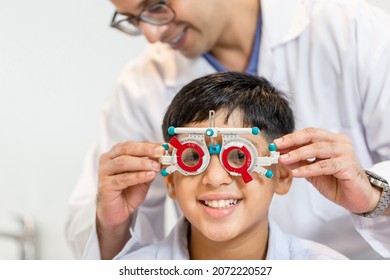Smiling Indian-thai boy choosing glasses in optics store, Boy doing eye test checking examination with optometrist using trial frame in optical shop - Powered by Shutterstock