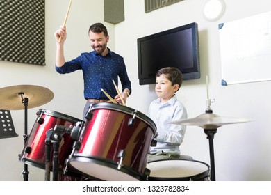 Smiling Instructor Playing Drums With Student During Music Class