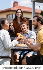 Smiling Interracial Friends Spending Time During Bbq Party With Wine Outdoors