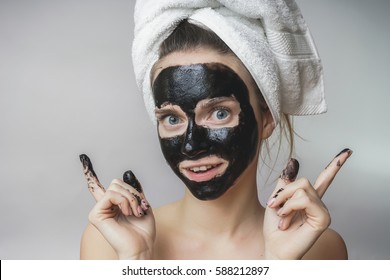 Smiling joyful woman gets black mask on face.Skin care,clean pores