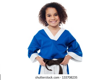 Smiling Karate Kid Posing To The Camera While Adjusting Her Brown Belt.