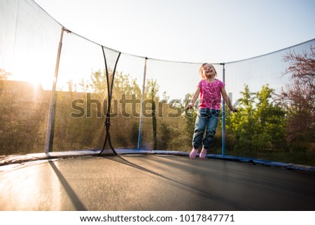 Smiling kid in the backyard bouncing on trampoline