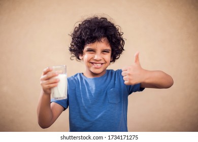 Smiling Kid Boy Holds Glass Of Milk And Shows Thumb Up Gesture. Children, Healthcare And Food Concept