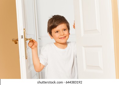 Smiling Kid Boy Opening The White Door At Home