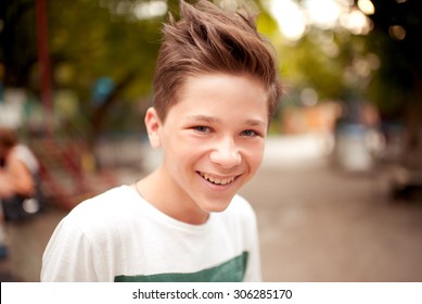 Smiling kid boy with stylish hairstyle outdoors. Looking at camera. Teenage boy