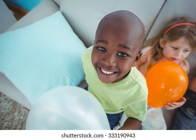 Smiling kids playing with balloons on the couch - Powered by Shutterstock