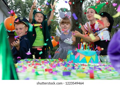 Smiling kids wearing in carnival costumes during colorful birthday party with cake - Powered by Shutterstock