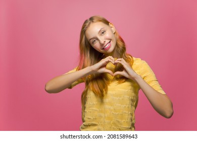 Smiling kind friendly young girl showing heart gesture feeling love. Charity, donation, gratefulness, support concept. - Shutterstock ID 2081589643