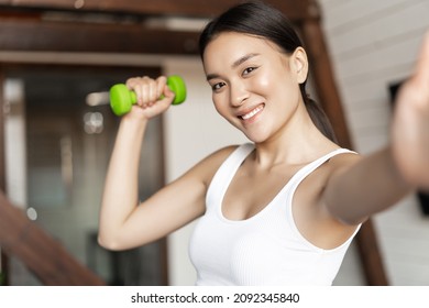 Smiling korean girl taking selfie with dumbbell, workout at home during pandemic, wearing activewear - Powered by Shutterstock