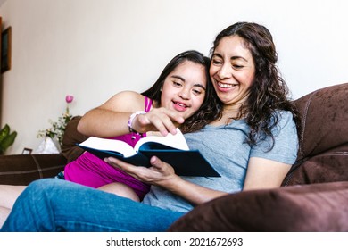 Стоковая фотография: Smiling latin teen girl with down syndrome and her mom reading a book at home, in disability concept in Latin America