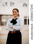 Smiling Latina businesswoman strides confidently through urban streets.