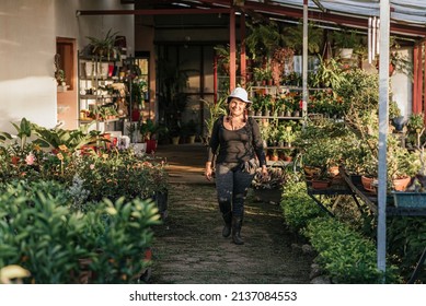 Smiling Latina Woman Walking Amidst Many Plants In A Plant Nursery 