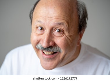 Smiling And Laughing 60s Year Old Senior Man Candid Close Up Portrait In Human Emotions And Facial Expressions Concept Isolated In Neutral Background.