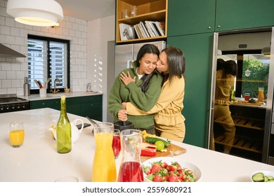 Smiling lesbian couple embracing in kitchen - Powered by Shutterstock