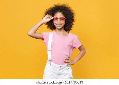 Smiling Little African American Kid Girl 12-13 Years Old In Pink T-shirt Eyeglasses Isolated On Yellow Background Studio Portrait. Childhood Lifestyle Concept. 