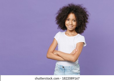 Smiling little african american kid girl 12-13 years old in white t-shirt isolated on pastel violet background studio portrait. Childhood lifestyle concept. Mock up copy space. Holding hands crossed