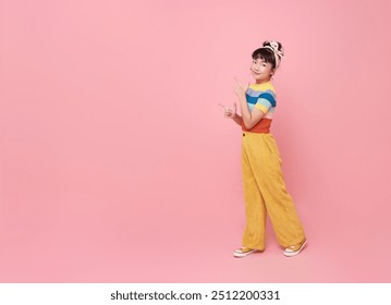 Smiling little asian girl looking and pointing finger shows place for your advertising text Isolated on pink background. - Powered by Shutterstock