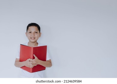 Smiling little boy hugging book isolated on white background with copy space. World book day and book mockup concept