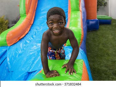 Smiling little boy sliding down an inflatable bounce house