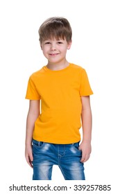 A smiling little boy in a yellow shirt stands against the white background