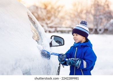 smiling little child boy helping to brush snow from fathers car - Powered by Shutterstock