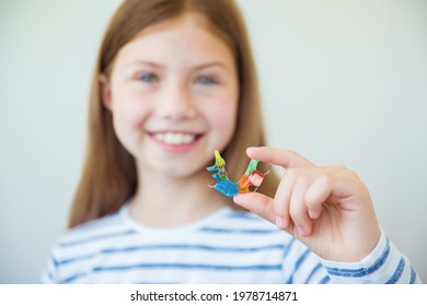 Smiling little child girl holds metal bright and colorful plate for align the teeth and bite. Orthodontist treats teeth