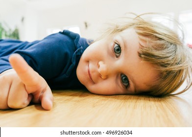 Smiling Little Child Laying On The Floor 