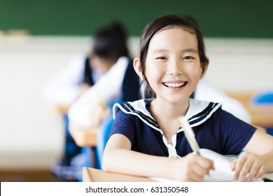 smiling little girl in classroom and her friends in background