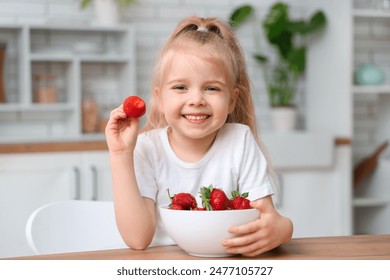 Smiling little girl eating strawberry in kitchen - Powered by Shutterstock