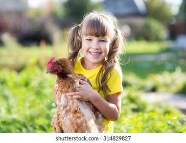 smiling little girl with a hen in front of the farm - Powered by Shutterstock