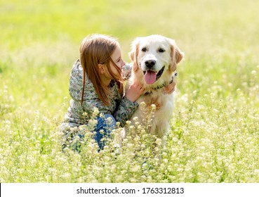 Smiling little girl looking at cute dog sitting in flowers on sunny field - Shutterstock ID 1763312813