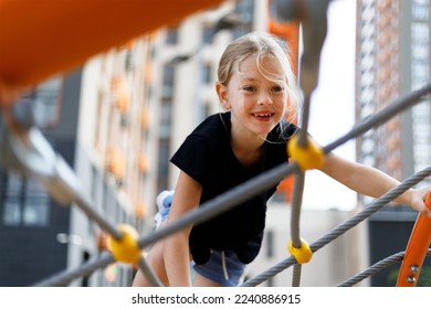 Smiling little girl on the playground, climbing rope net. - Powered by Shutterstock