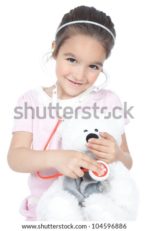 Smiling little girl playing doctor with stethoscope and teddy bear, isolated over white