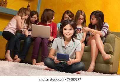 Smiling little girl playing video game on portable console with her friends - Powered by Shutterstock