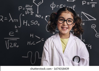 smiling little girl science student with glasses in lab coat on school blackboard background with hand drawings science formula pattern, back to school and successful female career concept - Shutterstock ID 1674318439