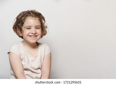 Smiling Little Girl With Short Hair And Light Clothes Isolated On Light Background