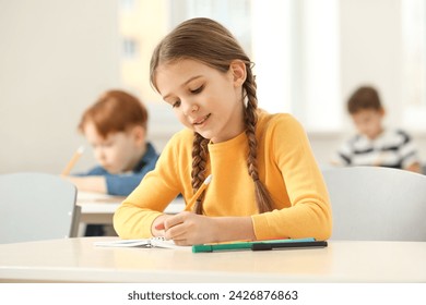 Smiling little girl studying in classroom at school - Powered by Shutterstock