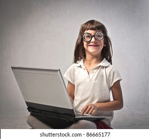 Smiling Little Girl With Thick Eyeglasses Using A Laptop