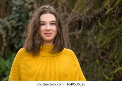 Smiling long-haired teenager girl in a yellow sweater outdoors portrait