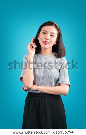 Smiling lovely asian woman dressed in pin-up style dress over blue.