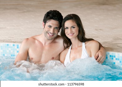 Smiling loving couple relaxing together on a jacuzzi pool at spa