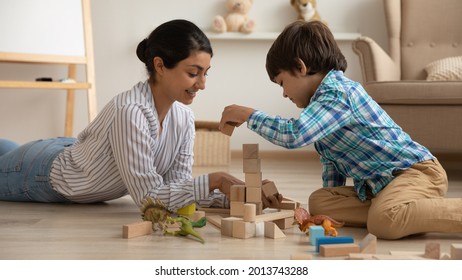 Smiling Loving Indian Mother And Little Son Playing With Toys Together, Lying On Warm Wooden Floor With Underfloor Heat, Happy Young Mom And Preschool Kid Having Fun At Home, Building From Blocks