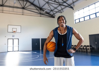 Smiling male african american basketball coach holding basketball in indoor gym, copy space. sports, coaching, athletics, training, mentor, team - Powered by Shutterstock