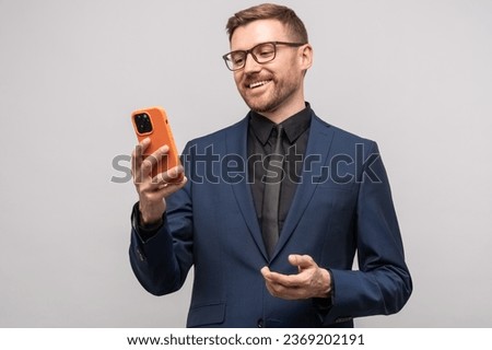 Smiling male businessman with smartphone. Happy successful man with mobile phone makes online electronic transaction merchant trader concludes lucrative contract on Internet, isolated on studio wall