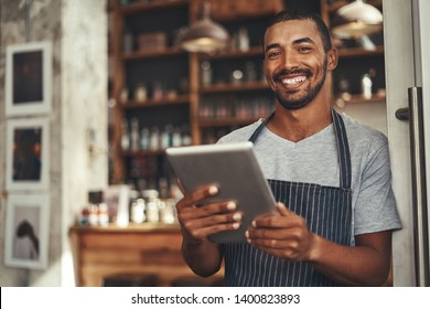 Smiling male cafe owner holding digital tablet in his hand